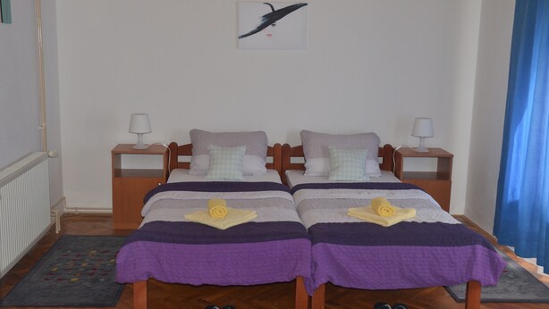 Une chambre double avec deux lits, chacun doté d’une table de chevet, d’une lampe et d’un coussin décoratif. Une œuvre d’art murale est visible au-dessus des lits.
