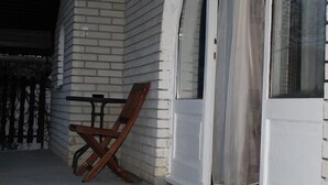 Un bâtiment en briques blanches avec une chaise en bois à l’extérieur.
