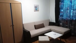 Un soggiorno con divano, un tavolino, un mobile e una finestra con tende.