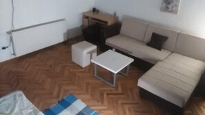 Un ambiente abitativo piccolo e accogliente con un divano, un tavolino e una TV su una mensola.