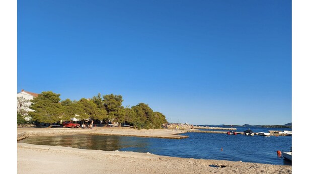 Uma área costeira com uma praia de areia, águas calmas e barcos.