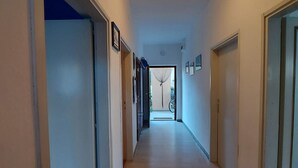 Um corredor com piso de madeira, paredes brancas e uma luminária no teto.