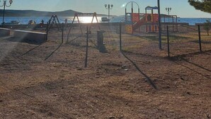 Um parque com brinquedos, cerca e postes de iluminação.