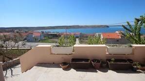 A balcony with potted plants and a view of a coastal town. - Njaco - Studio Apartment with Sea View (Razanac)