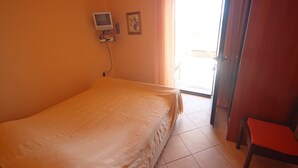A room with a bed, a television on the wall, a door, and a window with curtains. - Njaco - Studio Apartment with Sea View (Razanac)