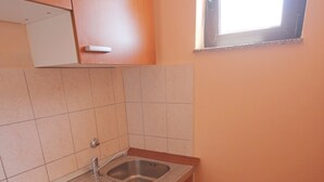 A compact kitchen with a sink, stove, and wooden cabinets. - Njaco - Studio Apartment with Sea View (Razanac)