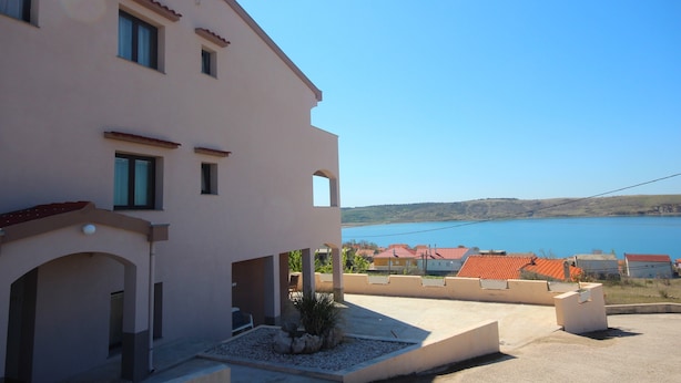 A building with a flat roof, multiple windows, and a view of a body of water. - Njaco - Two Bedroom Apartment with Terrace and Sea View (Razanac)
