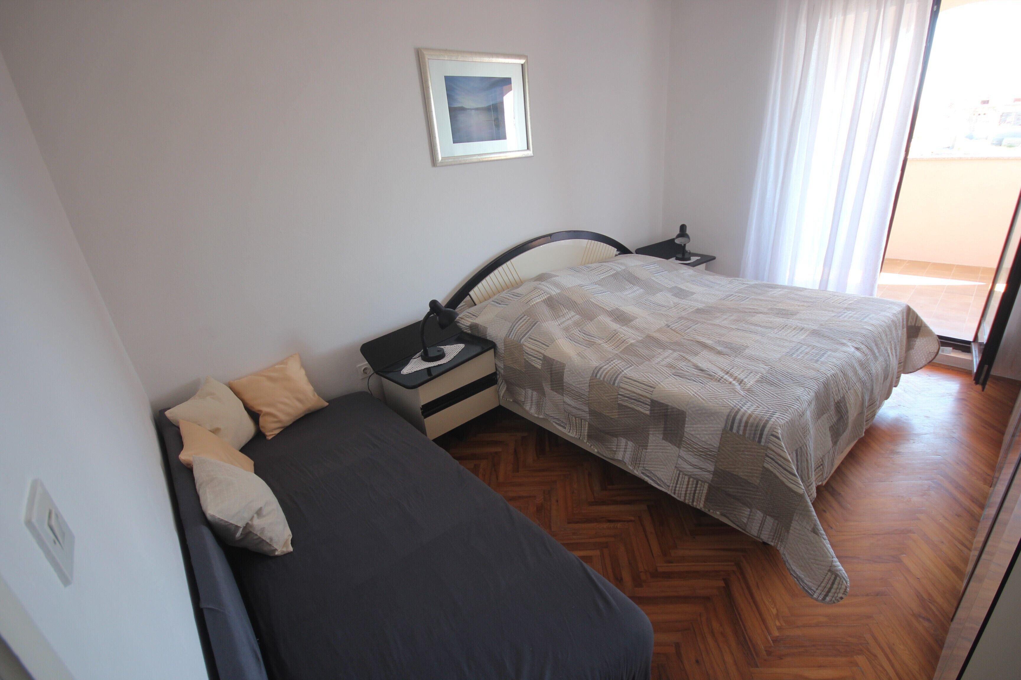 A bedroom with a bed, bedside table, and a framed picture on the wall.