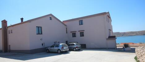 A two-story building with a flat roof and a parking area in front.