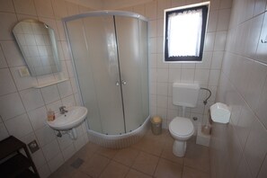 Baño con ducha, lavamanos, inodoro y ventana.