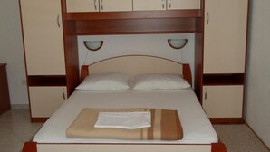 Een eenpersoonsbed met een houten hoofdbord, twee nachtkastjes en een tweezijdige garderobe.