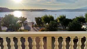 Un balcón con vistas a un lago, árboles y una cadena montañosa distante.
