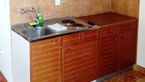 Een keuken met houten kastjes, een roestvrijstalen spoelbak en een betegelde achterwand.
