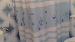 A bathroom with a shower curtain featuring a blue and white striped pattern with cartoon fish and seaweed. - Apartments Branko - Economy Studio Apartment with Balcony and Sea View (A4) (Nin)