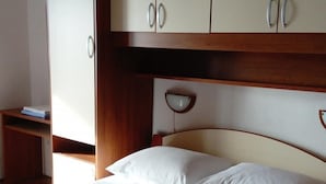 A hotel room with a bed, a wooden wardrobe, and a desk. - Apartments Branko - Economy Studio Apartment with Balcony and Sea View (A4) (Nin)