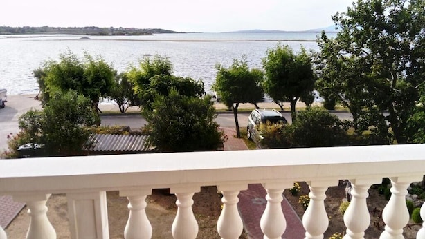 A balcony with a view of a body of water, trees, and parked cars. - Apartments Branko - Economy Studio Apartment with Balcony and Sea View (A4) (Nin)