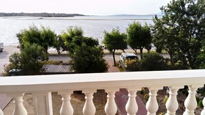 A balcony with a view of a body of water, trees, and parked cars. - Apartments Branko - Economy Studio Apartment with Balcony and Sea View (A4) (Nin)