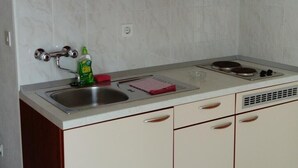A kitchen with white cabinets, a stainless steel sink, and a gas stove. - Apartments Branko - Traditional Studio Apartment with Balcony and Sea View (A6) (Nin)