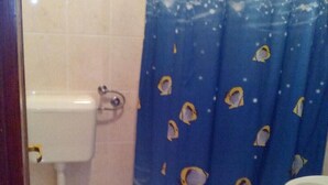 A bathroom with a toilet, sink, and shower curtain with fish patterns. - Apartments Branko - Traditional Studio Apartment with Balcony and Sea View (A6) (Nin)