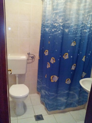 Een badkamer met toilet, wastafel en douchegordijn met vismotieven.