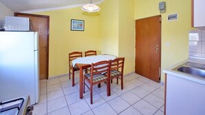 Eine kleine Küche mit Esstisch, Stühlen, Kühlschrank und Spüle.