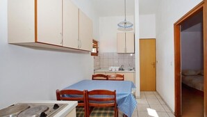 Una cocina compacta con una mesa, sillas y estufa.