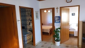 A hallway with a bed, a potted plant, and a cross on the wall. - Apartment Rina- Two Bedroom Apartment with Terrace (Mandre)