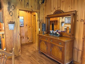 Interior de madera con un armario, un espejo y un cartel que indica un baño.