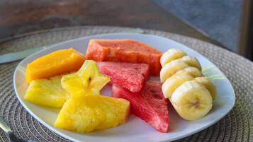 Une assiette de fruits coupés en tranches, notamment de l’ananas, de la pastèque et des bananes.