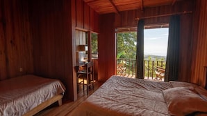 A wooden cabin with two beds, a desk, and a balcony with a view. - Hotel Flor de Bromelia (Monteverde)
