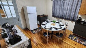 Une cuisine compacte comprenant une table de salle à manger ronde, un réfrigérateur, une cuisinière et un évier.