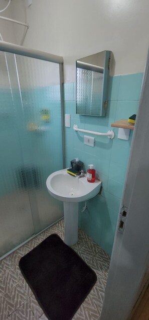 A bathroom with a shower, a sink, and a mirror. - Casa aconchegante e prática (Cascavel)