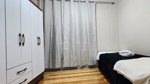 Une chambre à coucher avec un lit, une armoire et un rideau.