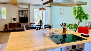 A modern kitchen with a wooden island, a red appliance, and a dining area with a bookshelf and a TV. - Chez Georges - House 3 - Lakes and Gorges du Verdon (ESPARRON DE VERDON)