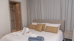 A hotel room with a bed, a nightstand, a wardrobe, and a bathroom visible through an open door. - Ocean view house with pool & BBQ (Noord)