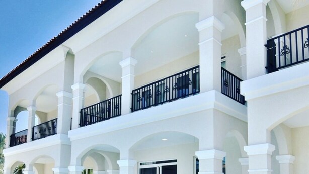 A hotel with a pool, outdoor seating, and a multi-level balcony with black railings.