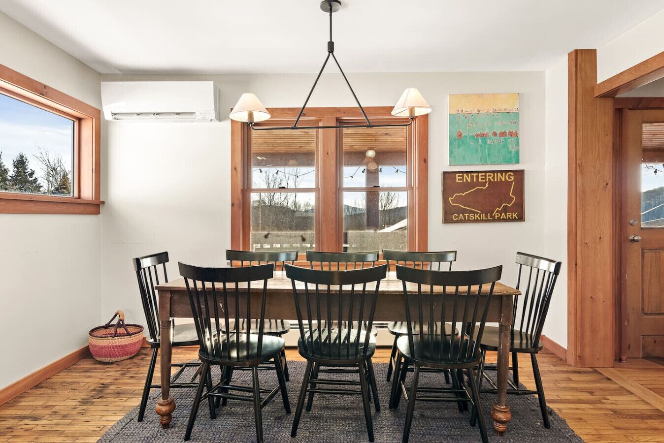 A dining area with a table and chairs, a window with a view, an air conditioning unit, and a sign on the wall.