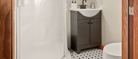 A bathroom with a shower, sink, and toilet.
