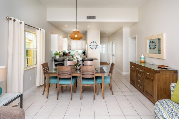 A dining area with a table, chairs, and a hanging light fixture.