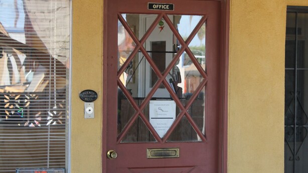 A red door with a glass panel and a sign above it that reads "OFFICE". - Cinderella Motel (Wasco)