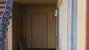 A building entrance with a metal staircase, a door, and a window. - Cinderella Motel (Wasco)