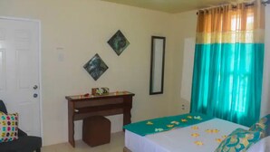 A bedroom with a bed, a desk, a chair, and a door. - 1, Bedroom Suites, of Leisure and SPA (Mayaro)