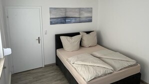 A bedroom with a bed, a door, and a wall-mounted painting. - A modern renovated apartment with balcony terrace. (Lübbecke)
