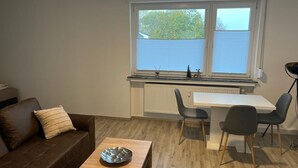 A compact living space with a kitchenette, a dining area, and a sofa. - A modern renovated apartment with balcony terrace. (Lübbecke)