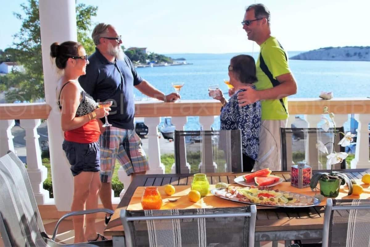 A terrace with a table set for a meal, overlooking a body of water.