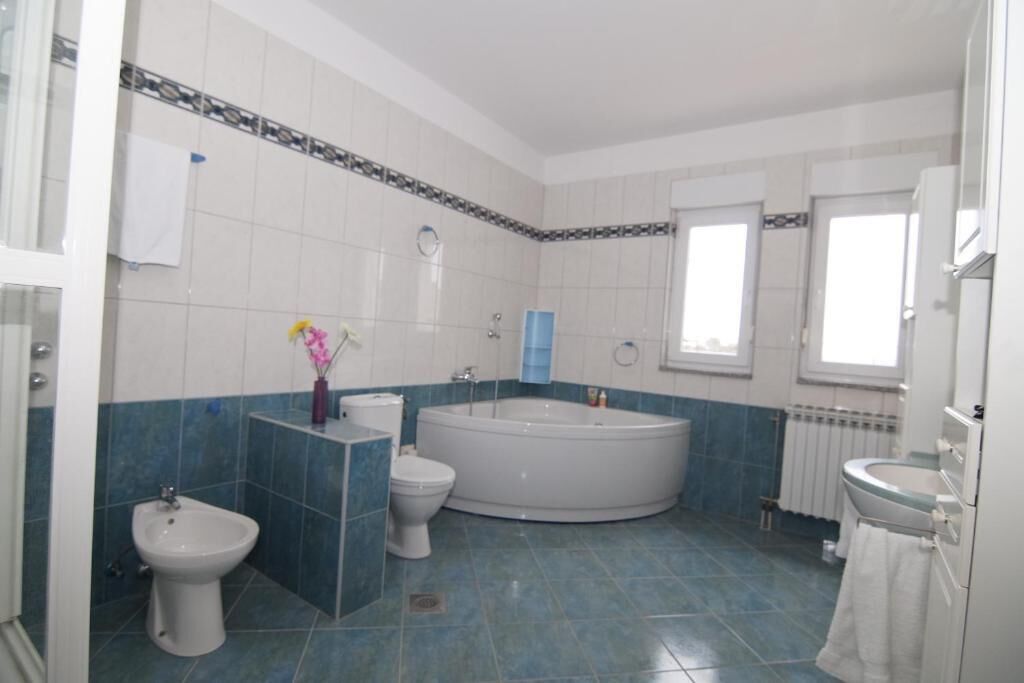 A bathroom with a bidet, toilet, bathtub, and a window.