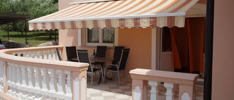 An outdoor patio with a checkered floor, a table with chairs, and a striped awning.