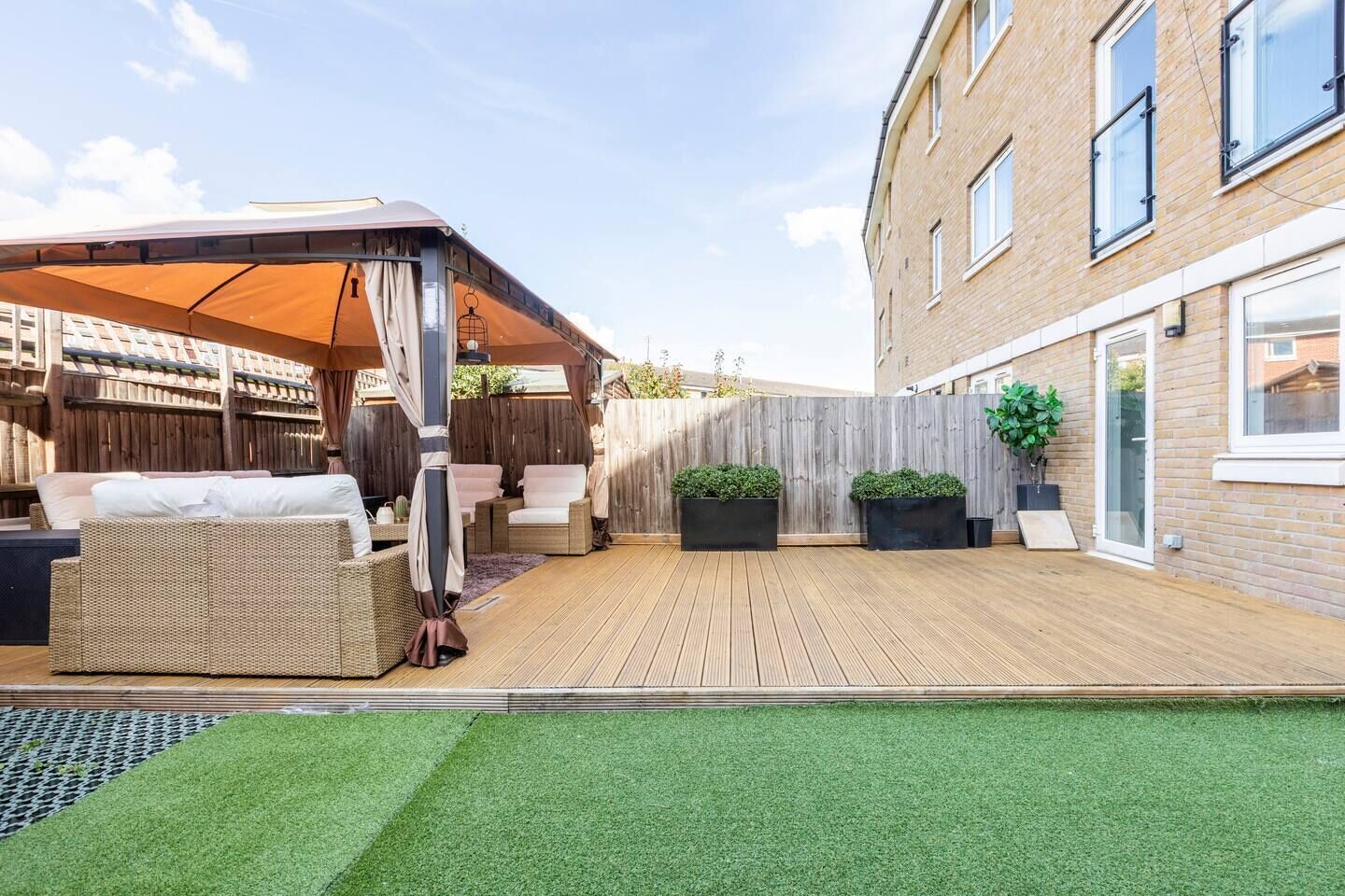 Une terrasse avec des meubles d’extérieur, un espace salon abrité et une plateforme en bois.