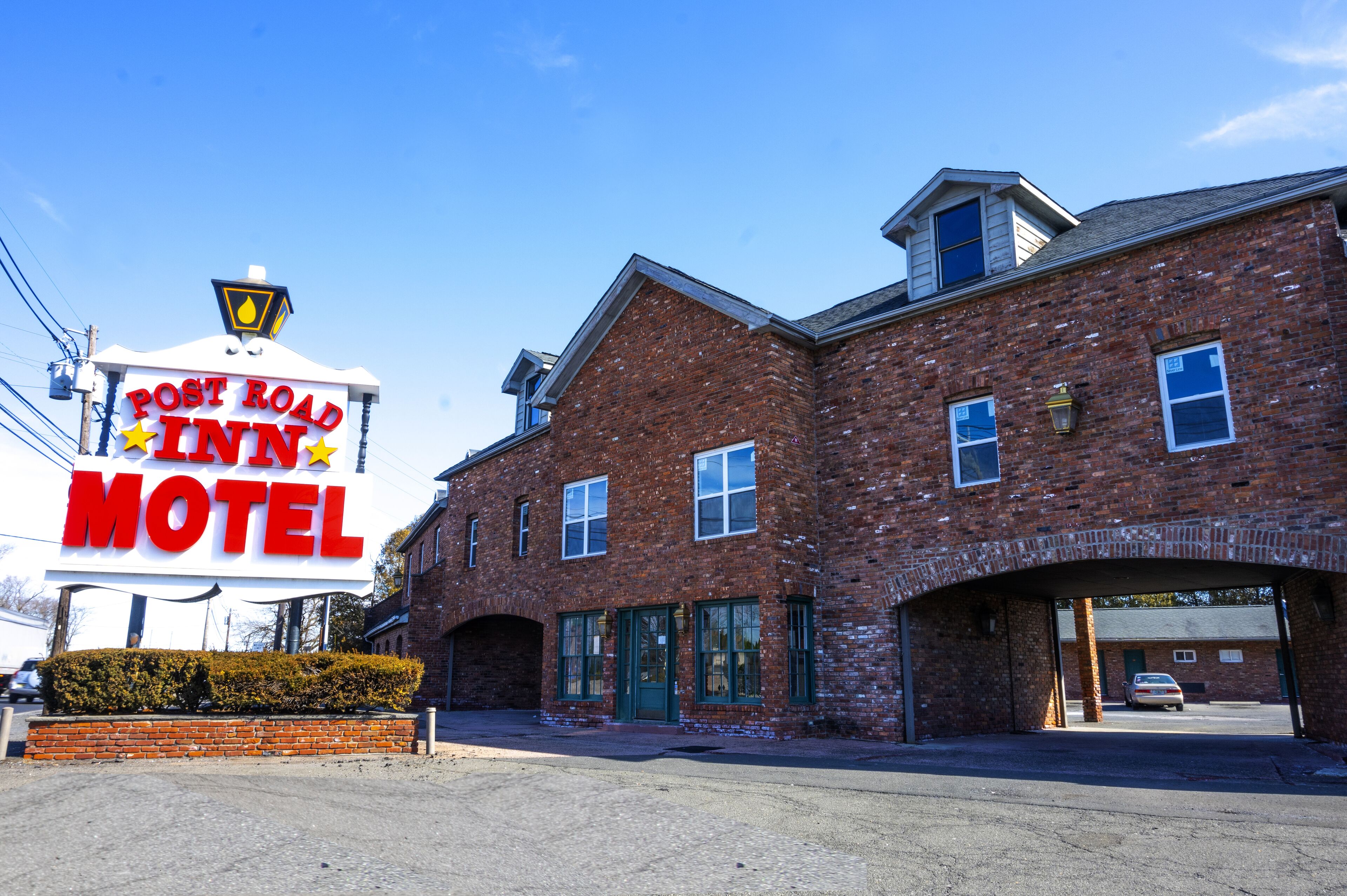 A brick motel with a large sign reading "Post Road Inn Motel".