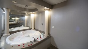 Une salle de bain avec une grande baignoire, un miroir et un lavabo.
